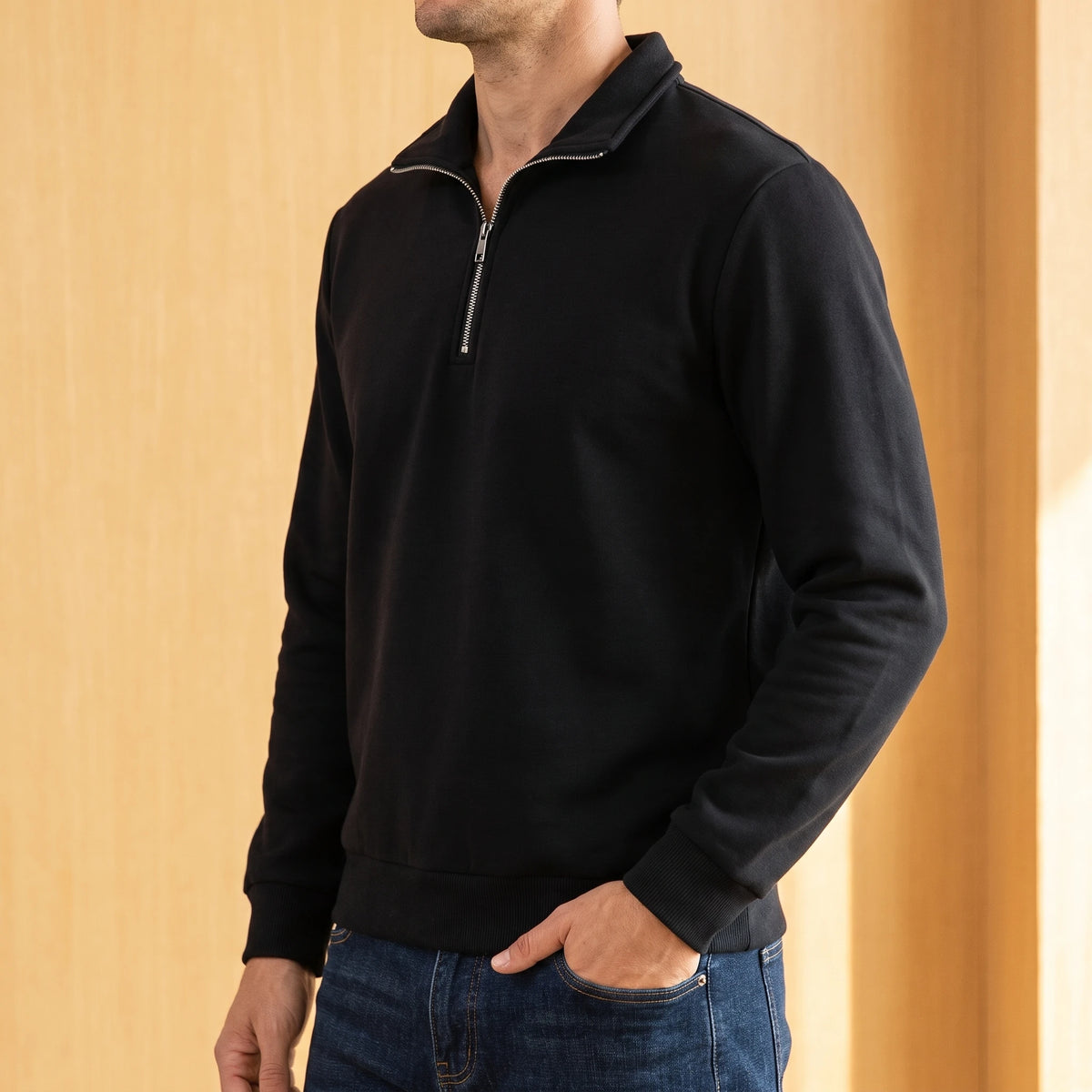 Man wearing the black half zip sweater with dark blue jeans, one hand in his pocket
