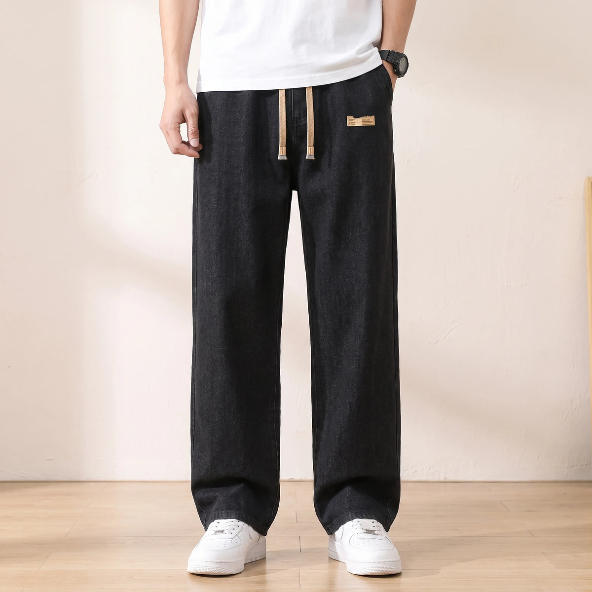 Black baggy drawstring jeans with a wide straight leg worn with white sneakers