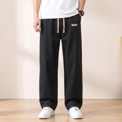 Black baggy drawstring jeans with a wide straight leg worn with white sneakers