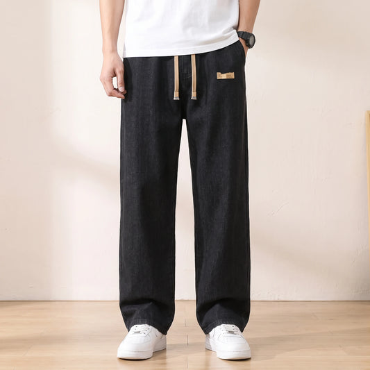 Black baggy drawstring jeans with a wide straight leg worn with white sneakers