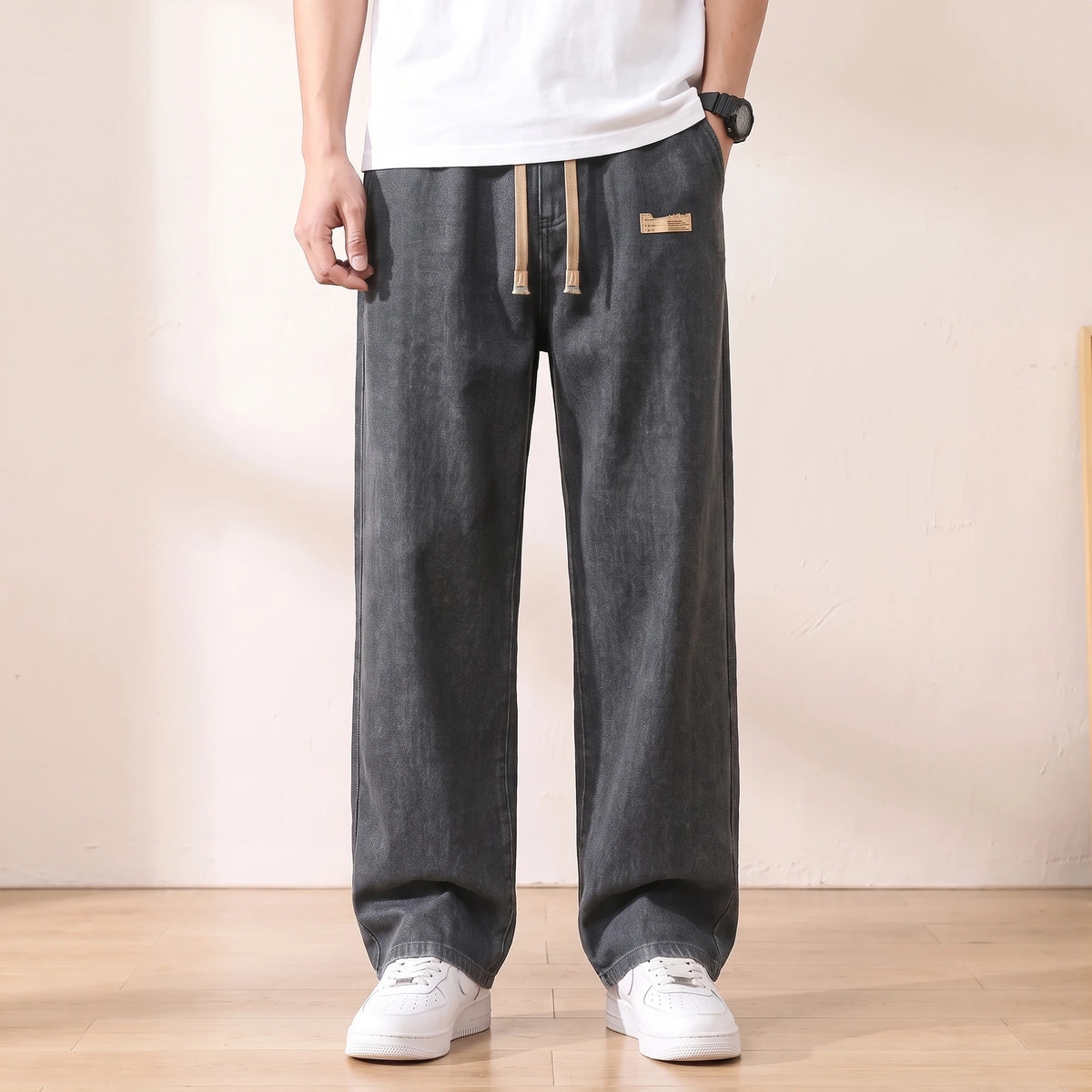 Grey baggy drawstring jeans with a wide straight leg worn with white sneakers