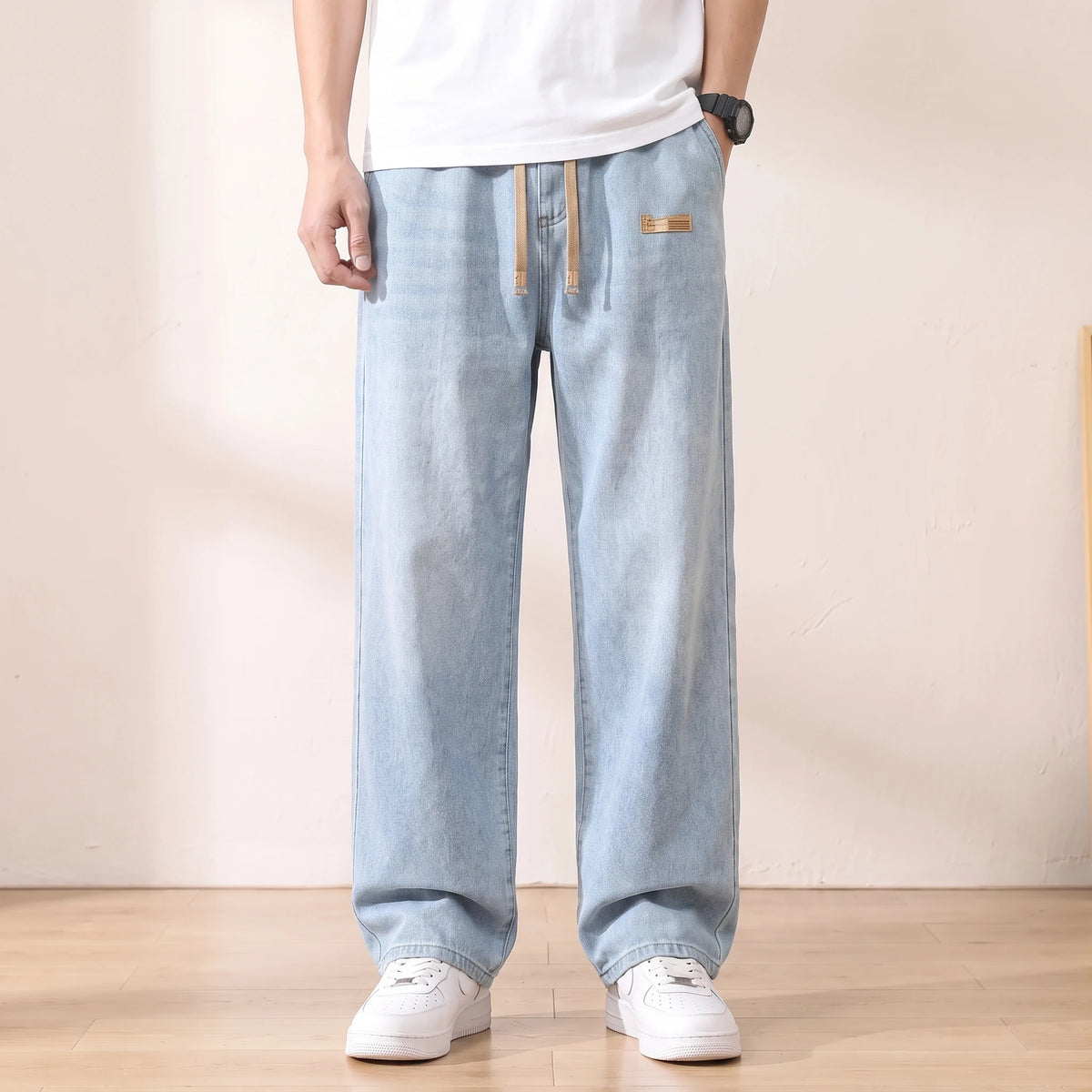 Light blue baggy drawstring jeans with a wide straight leg worn with white sneakers