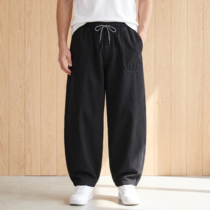 Black barrel leg trousers with a drawstring waist and large hip pockets worn with a white tee and sneakers