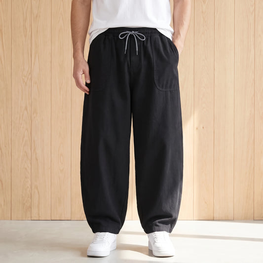 Black barrel leg trousers with a drawstring waist and large hip pockets worn with a white tee and sneakers