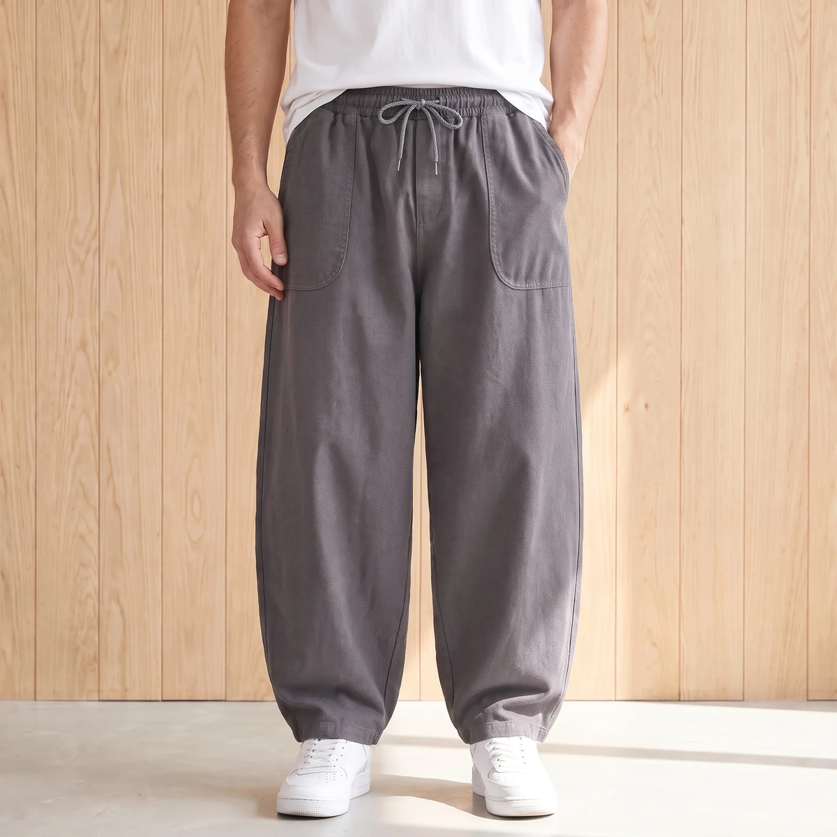 Grey barrel leg trousers with a drawstring waist and large hip pockets worn with a white tee and sneakers