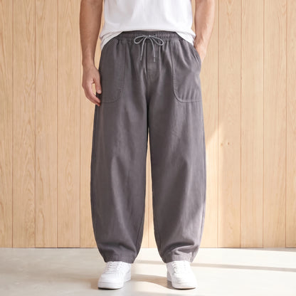 Grey barrel leg trousers with a drawstring waist and large hip pockets worn with a white tee and sneakers