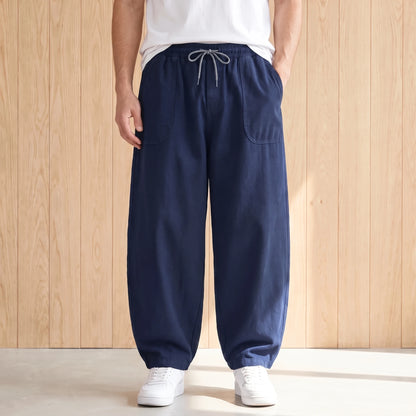 Navy blue barrel leg trousers with a drawstring waist and large hip pockets worn with a white tee and sneakers