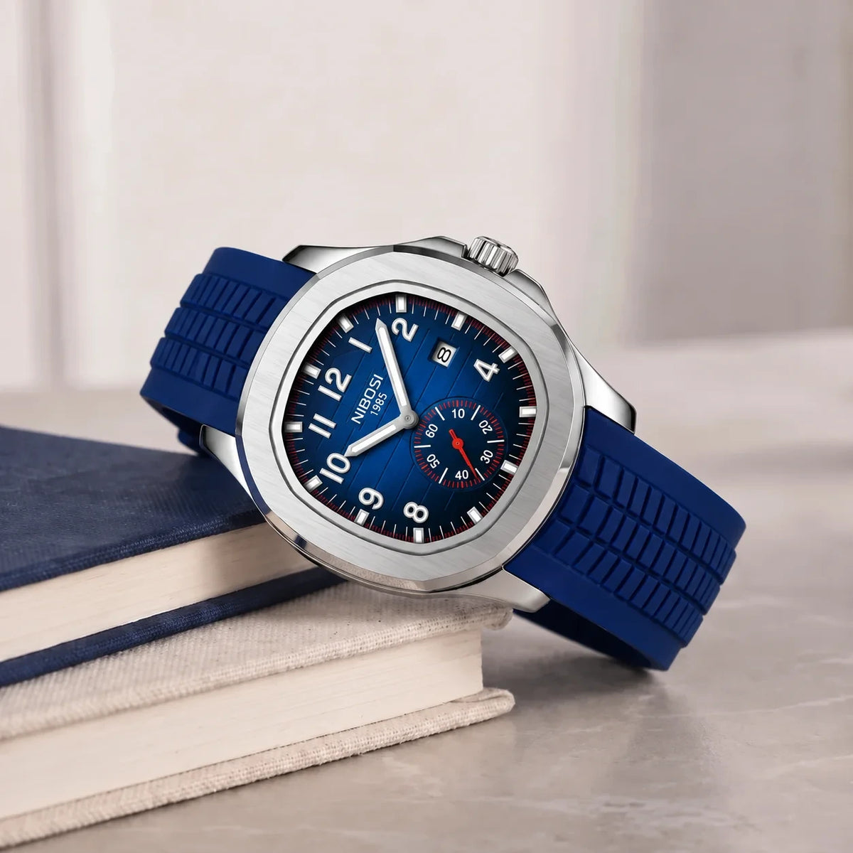 Blue strap sport watch with a blue dial on a book stack