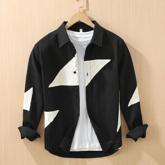 Black textured shirt with large cream contrast panels hanging on a wooden hanger