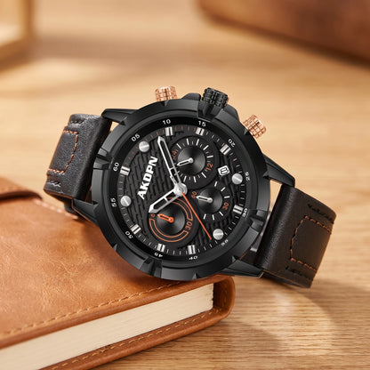 Black sports watch with rose-gold pushers and a black stitched leather strap resting on a tan notebook