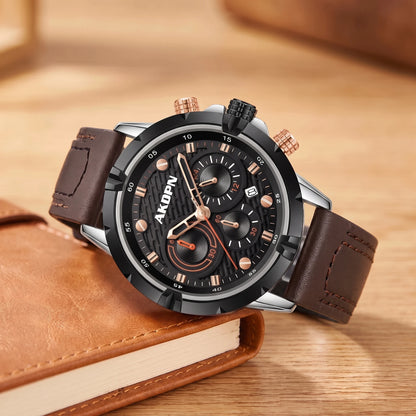 Silver sports watch with a black dial and a brown stitched leather strap resting on a tan notebook