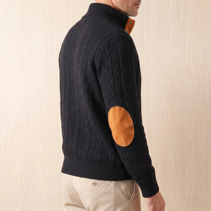 Man wearing the black cable knit sweater with beige chinos, seen from the side to show the elbow patch