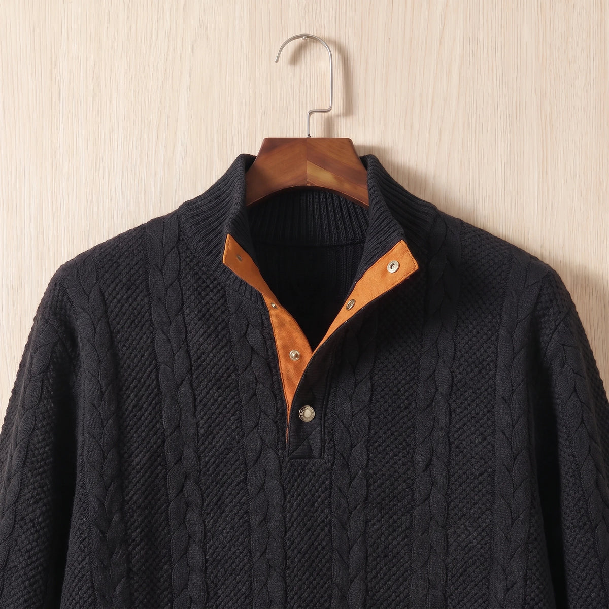 Close-up of the stand collar, two-button placket with tan facing and cable knit on the black sweater