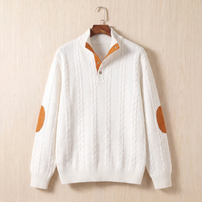 White cable knit sweater with a stand collar, button neck and tan elbow patches hanging on a wooden hanger