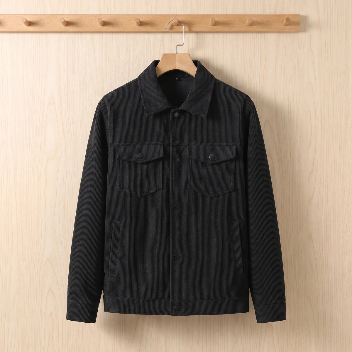 Men's black corduroy jacket hanging on a wooden hanger