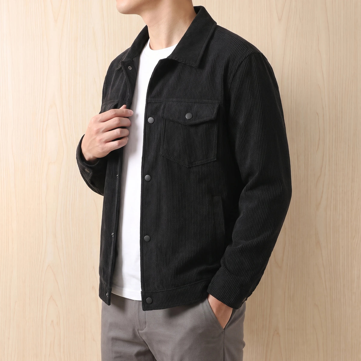 Man wearing the black corduroy jacket over a white tee, side view