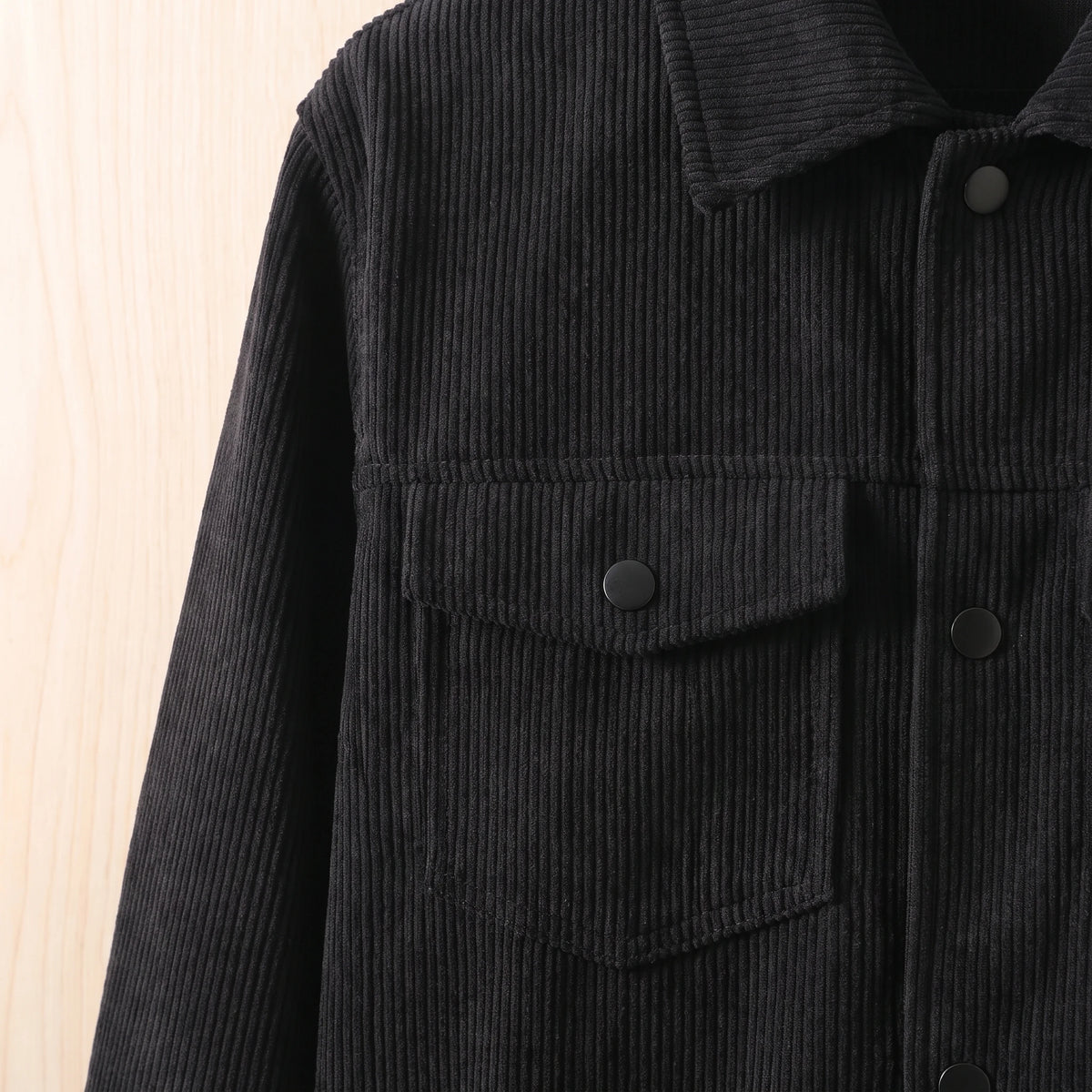 Close-up of the chest flap pocket and snap on the black corduroy jacket