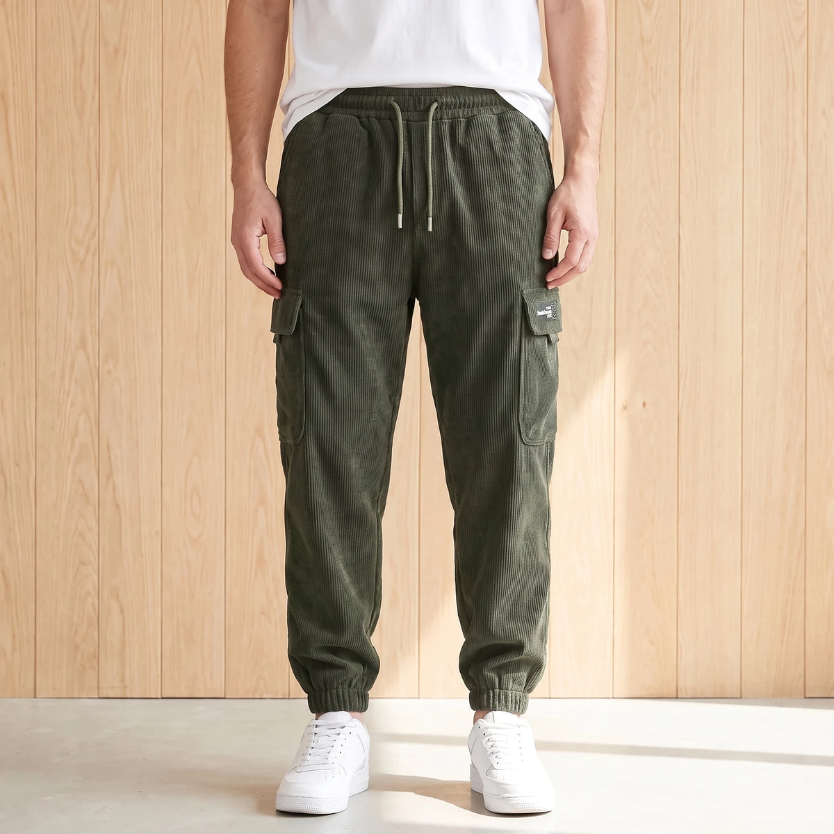 Green corduroy cargo joggers with a drawcord waist and large side pocket worn with white sneakers