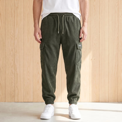 Green corduroy cargo joggers with a drawcord waist and large side pocket worn with white sneakers