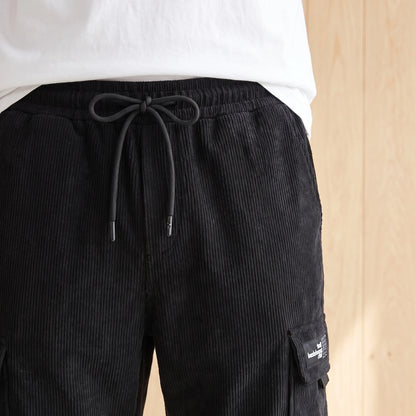 Close-up of the elastic drawcord waist on black ribbed corduroy cargo joggers