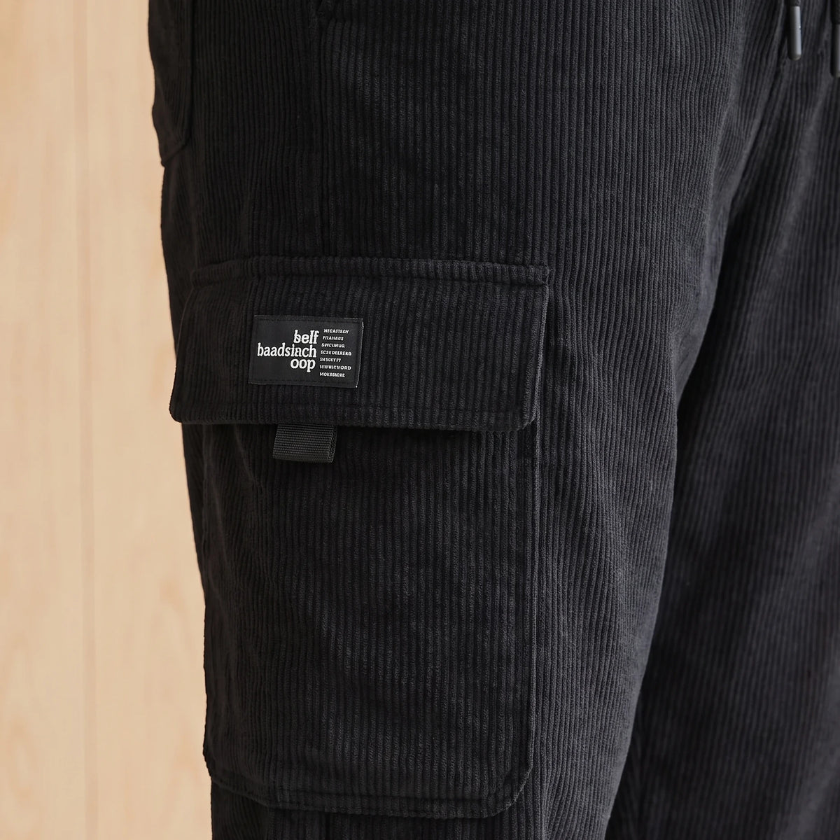 Close-up of the large side cargo pocket and label on black corduroy joggers