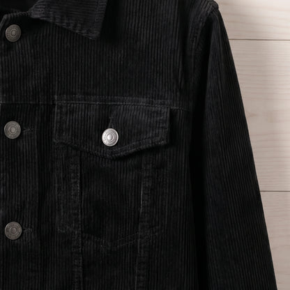 Close-up of the chest flap pocket and metal button on the black corduroy trucker jacket
