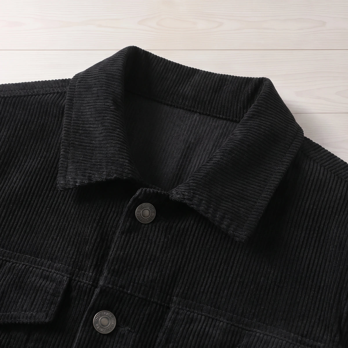 Close-up of the collar and metal buttons on the black corduroy trucker jacket