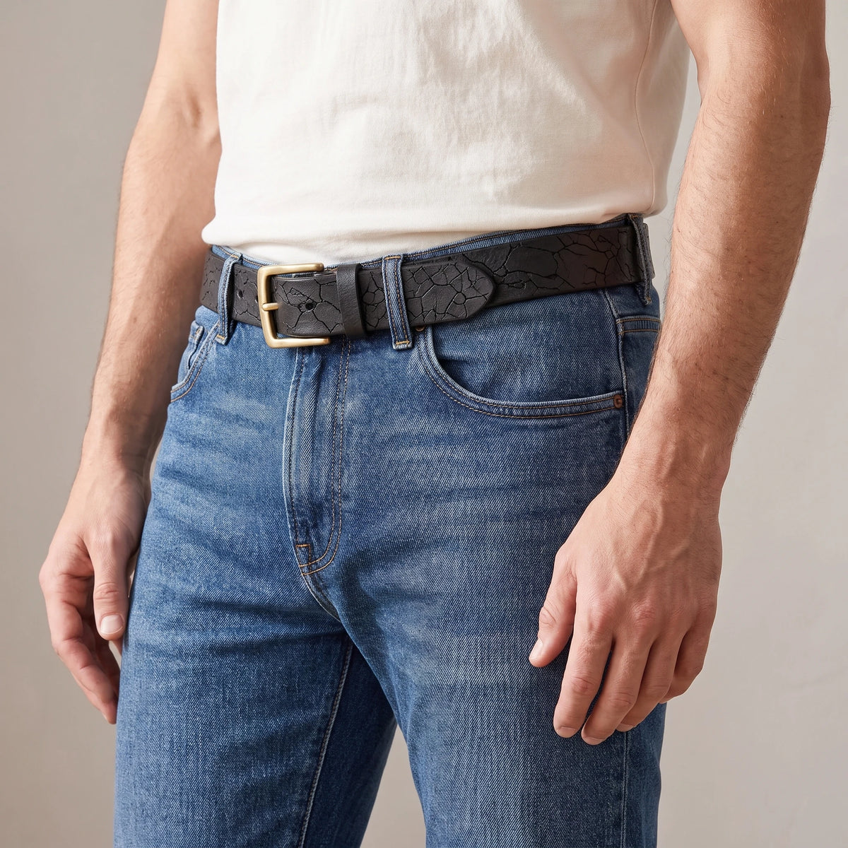 Man wearing the black cracked cowhide belt with blue jeans and an off-white t-shirt