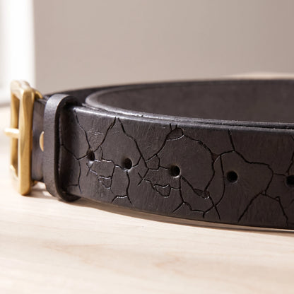 Close-up of the cracked leather pattern and holes on the black belt strap