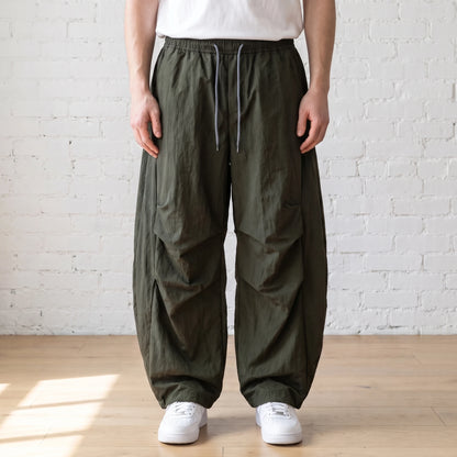 green crinkle wide leg pants worn with a white tee and trainers