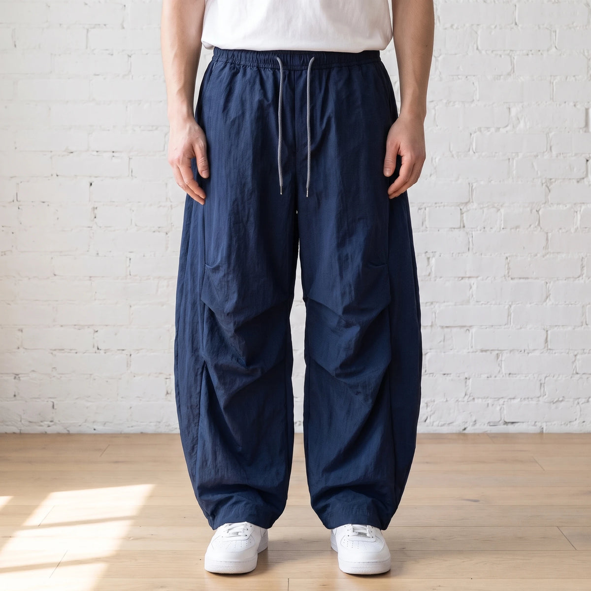 navy blue crinkle wide leg pants worn with a white tee and trainers