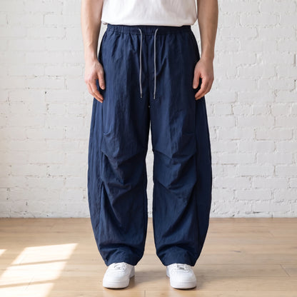 navy blue crinkle wide leg pants worn with a white tee and trainers