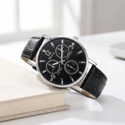 Black dial quartz watch with a black croc-grain strap resting on a cream book
