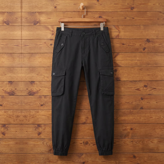 Black cuffed cargo joggers hanging on a wood wall