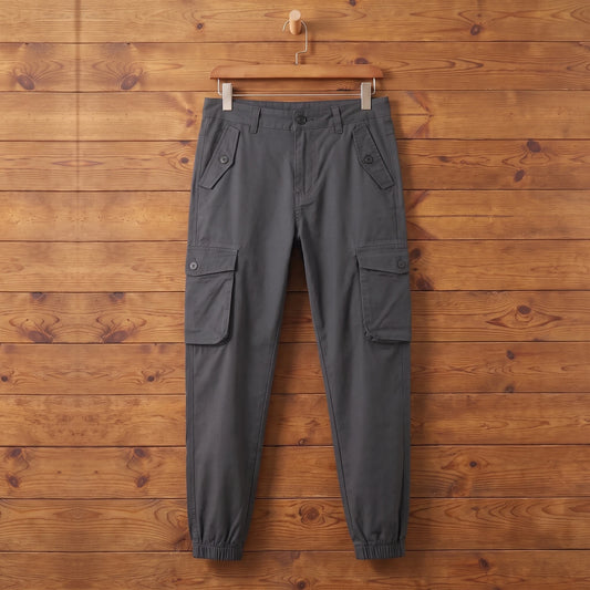 Grey cuffed cargo joggers hanging on a wood wall