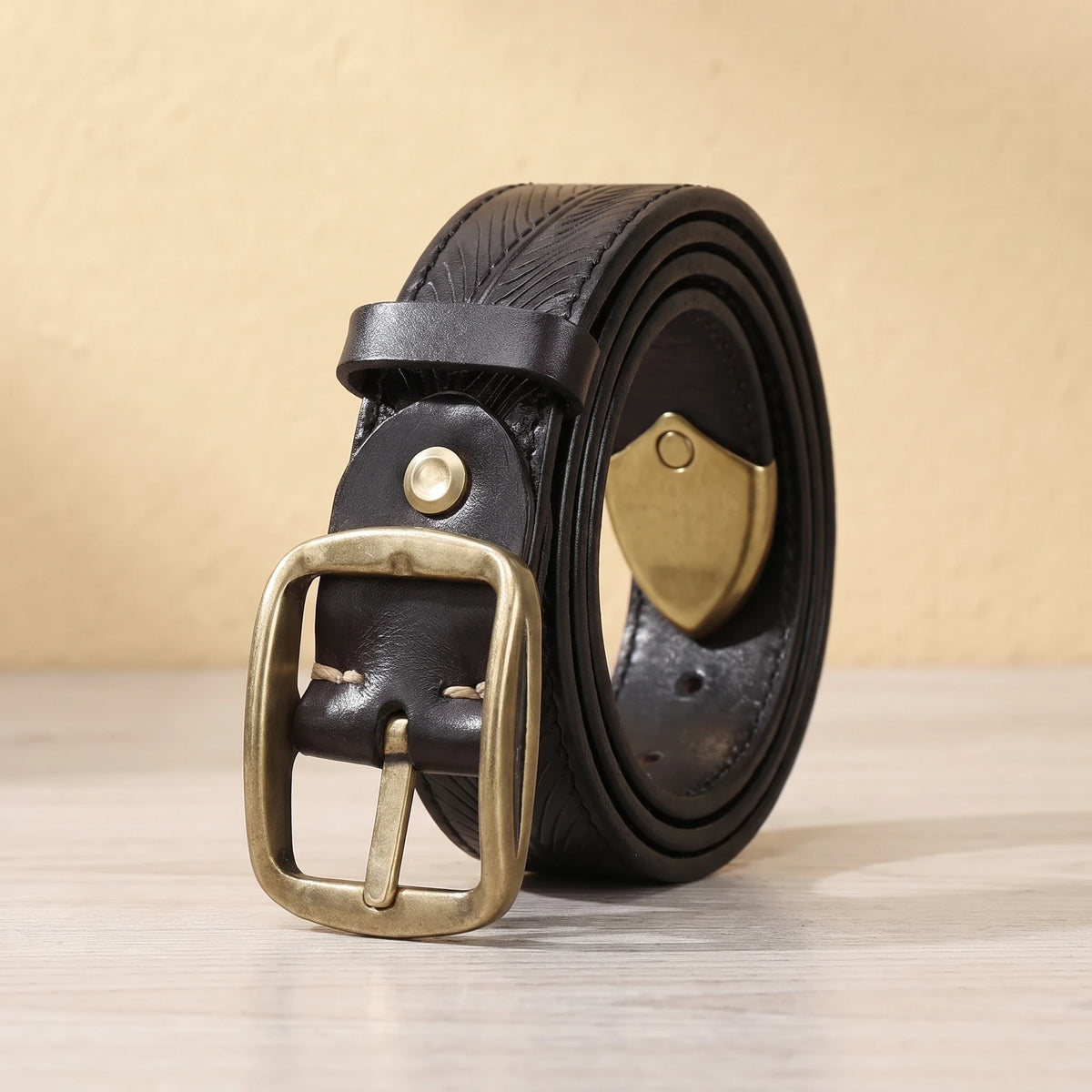 Black leather belt with feather pattern embossing, brass pin buckle and brass shield tip