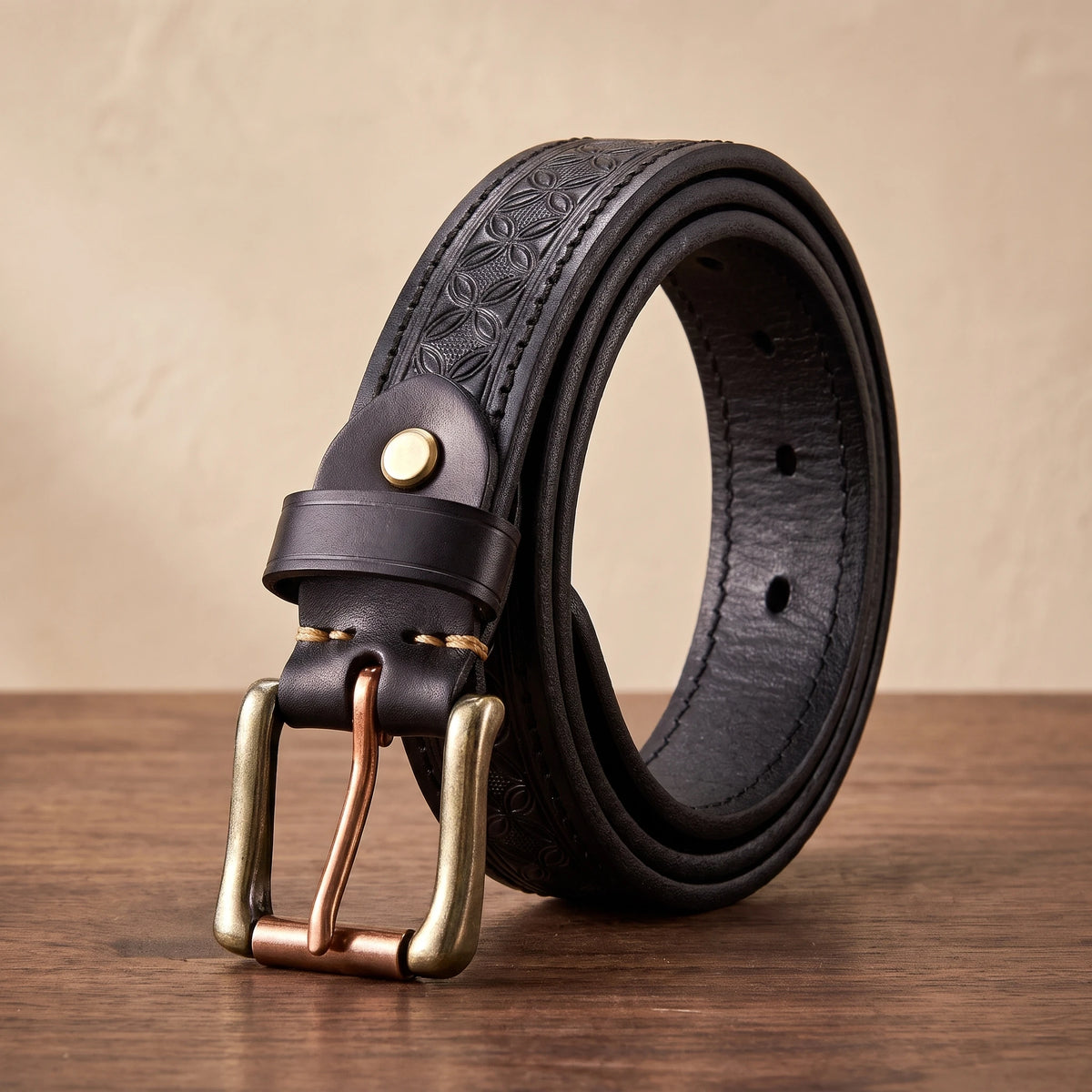 Black floral embossed leather belt with a brass buckle and copper roller bar