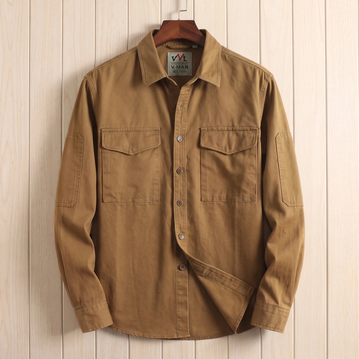 Brown heavy cotton overshirt with two flap chest pockets hanging on a wooden hanger