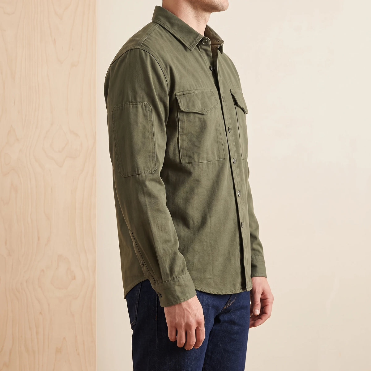 Side view of a man wearing a green heavy cotton overshirt with dark jeans