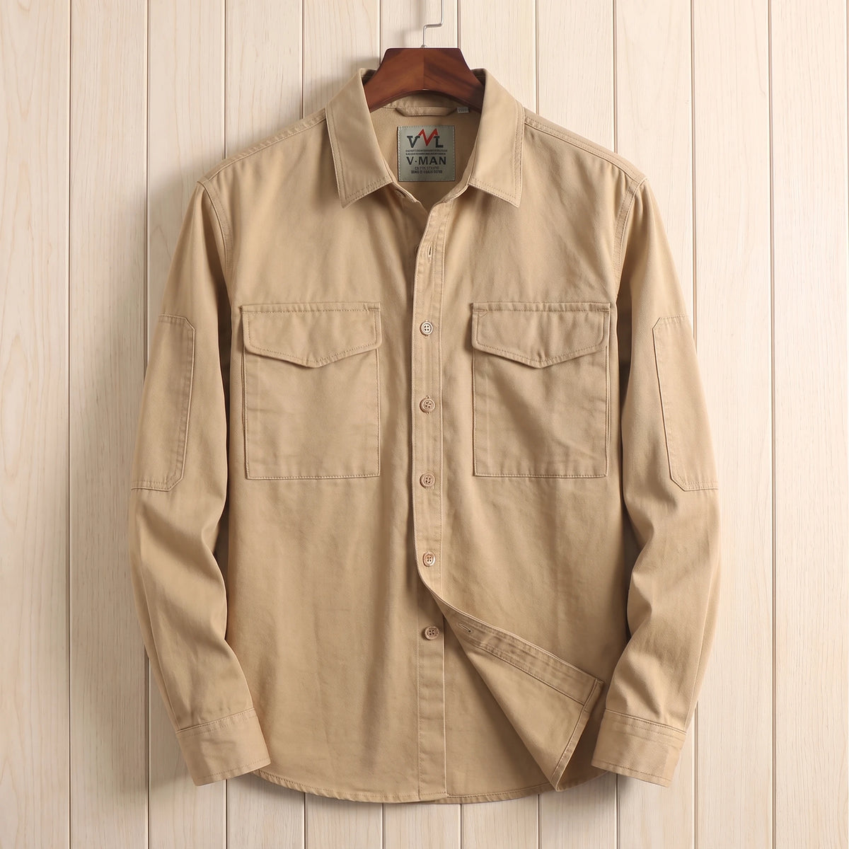 Khaki heavy cotton overshirt with two flap chest pockets hanging on a wooden hanger