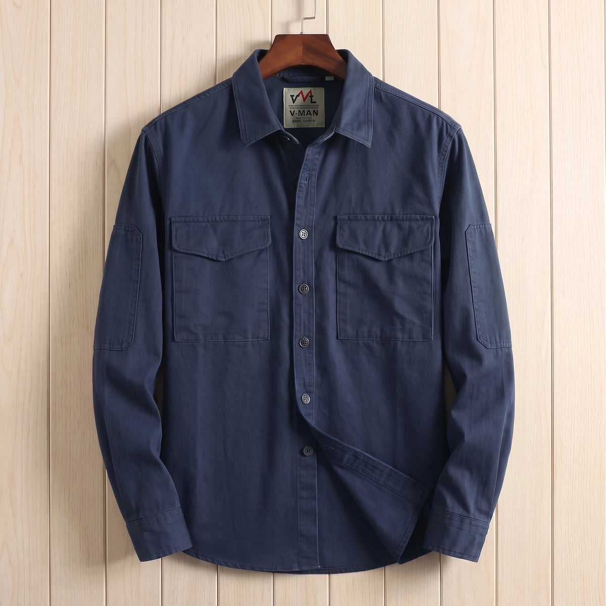 Navy blue heavy cotton overshirt with two flap chest pockets hanging on a wooden hanger