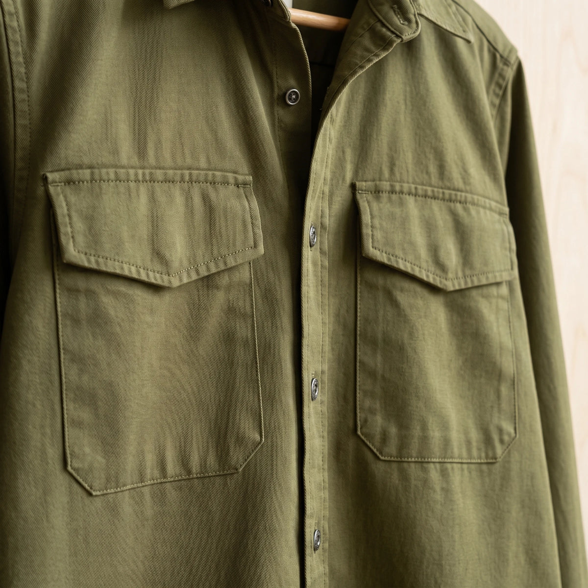 Close-up of the flap chest pockets and stitching on a green cotton overshirt