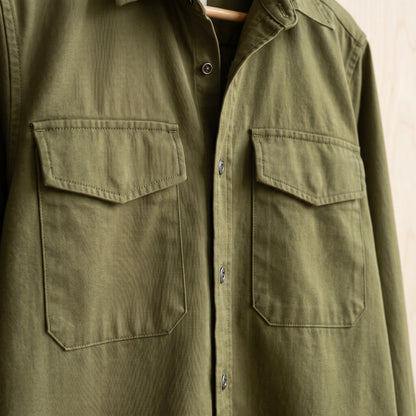 Close-up of the flap chest pockets and stitching on a green cotton overshirt