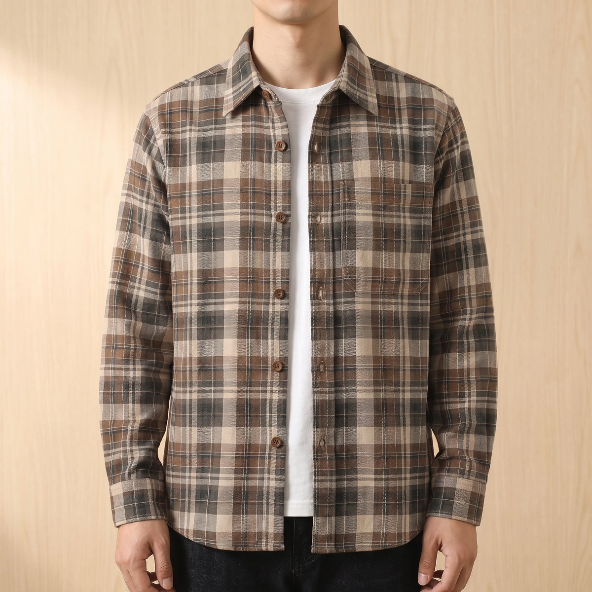 Man wearing a khaki brown plaid shirt open over a white tee