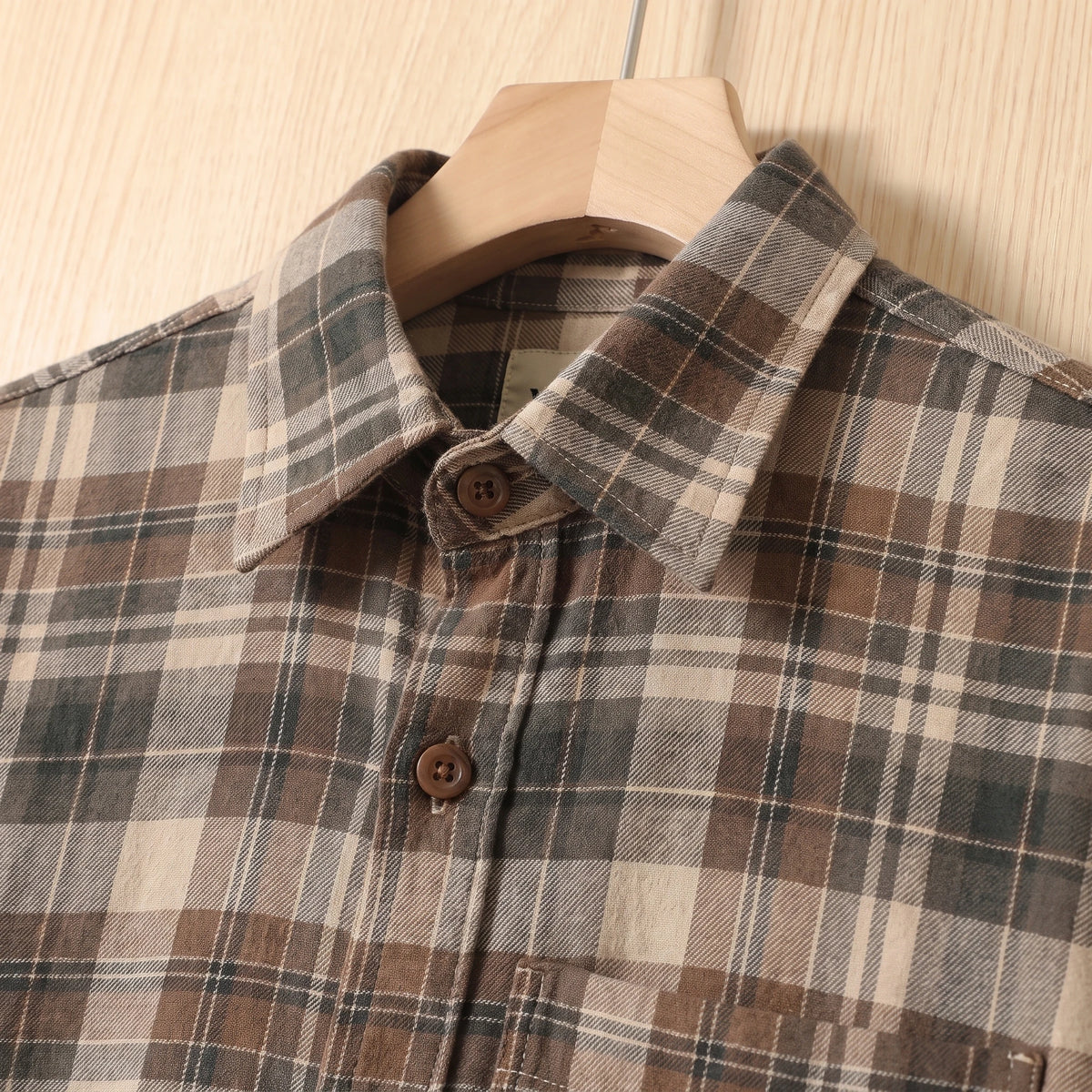 Close-up of the collar and buttons on a khaki brown plaid cotton shirt
