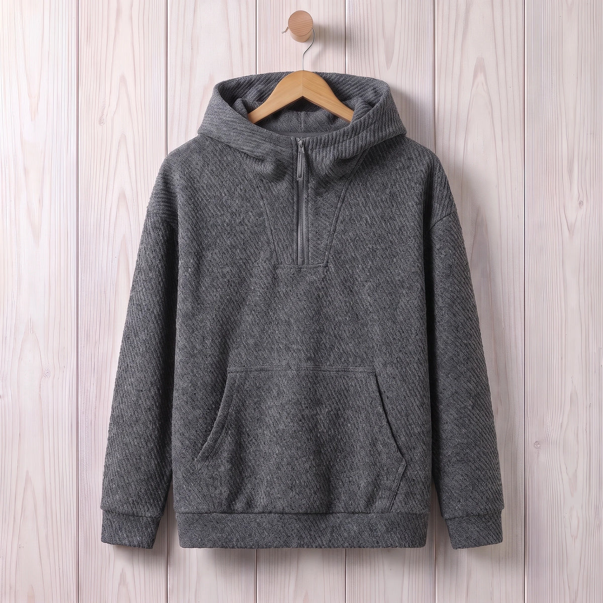 Dark grey loose hooded sweater with a short zip and kangaroo pocket hanging on a wooden hanger
