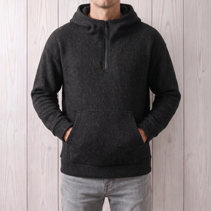 Man wearing the black hooded zip sweater with his hands in the front pocket and light grey jeans