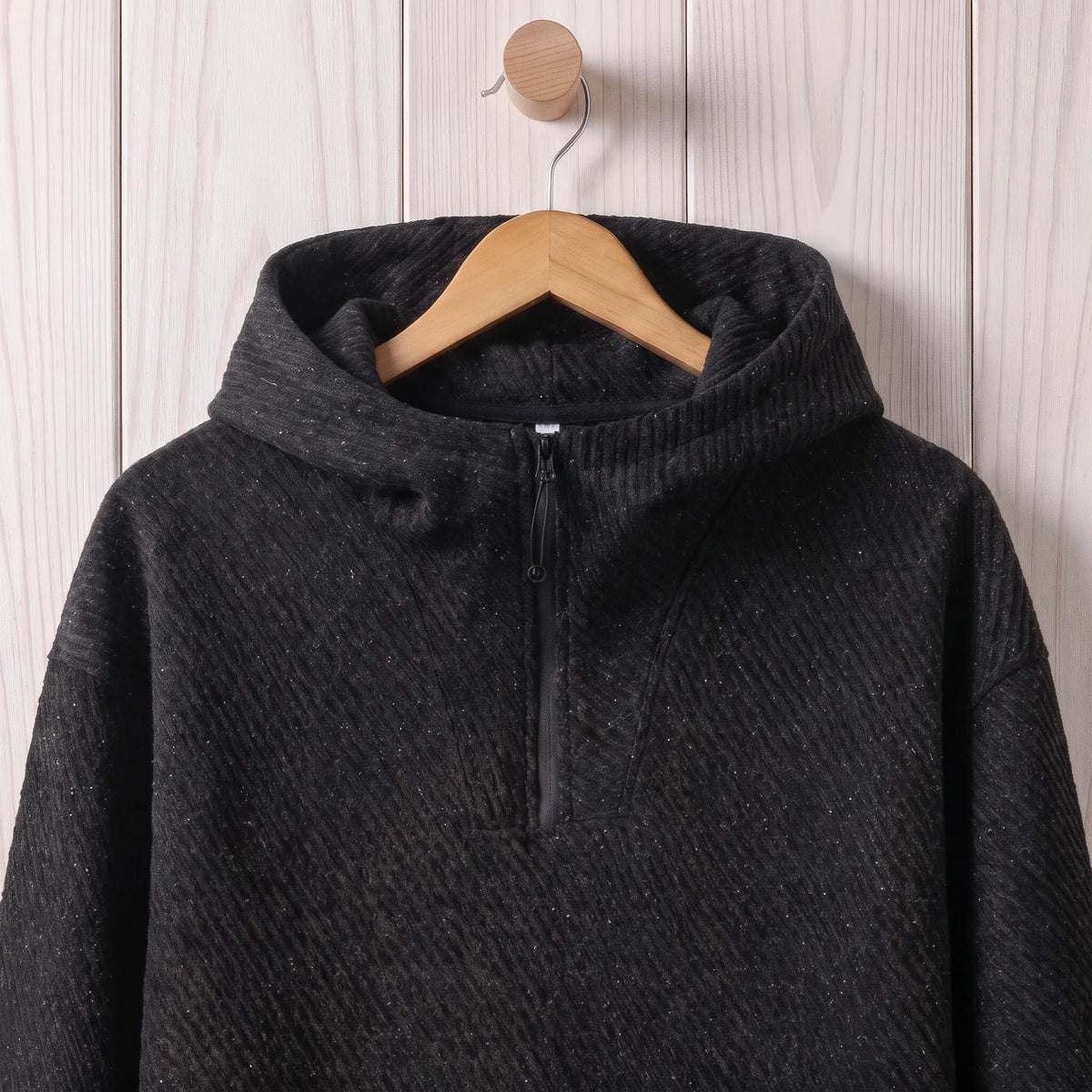 Close-up of the hood, short zip and diagonal textured fabric on the black hooded sweater