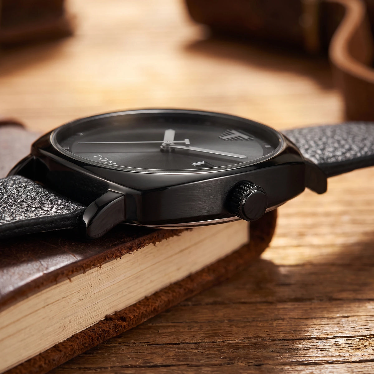 Side view of the black watch case, crown and leather strap