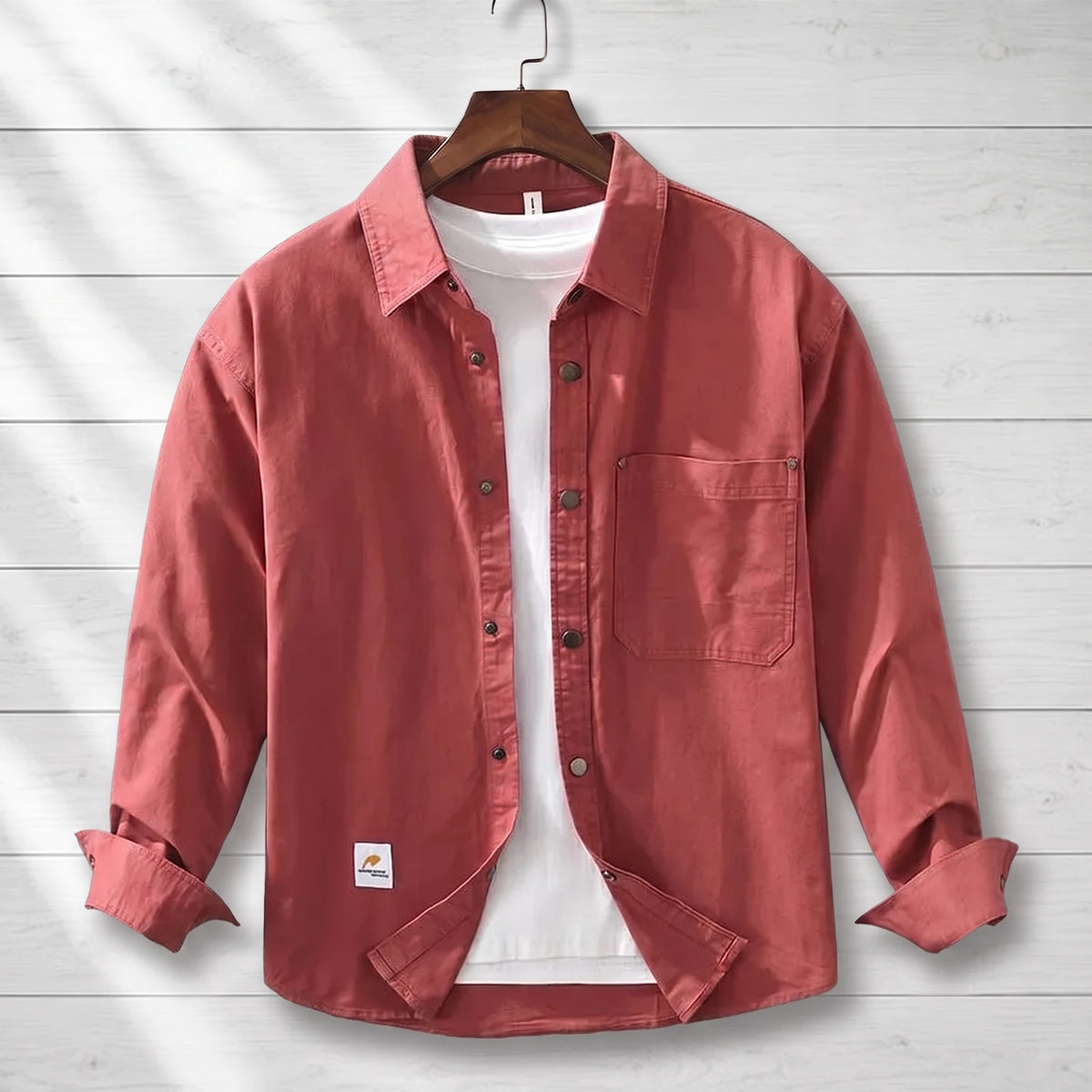 Red loose workwear shirt with a patch chest pocket hanging on a wooden hanger